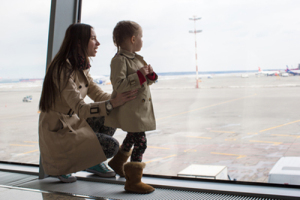 Mother and little daughter looking out the window at airport ter